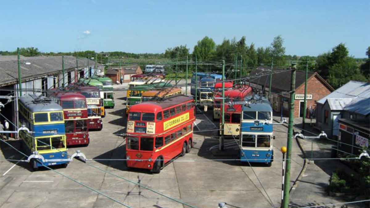 A collection of red buses and blue buses in the yard at Trolleybus Museum