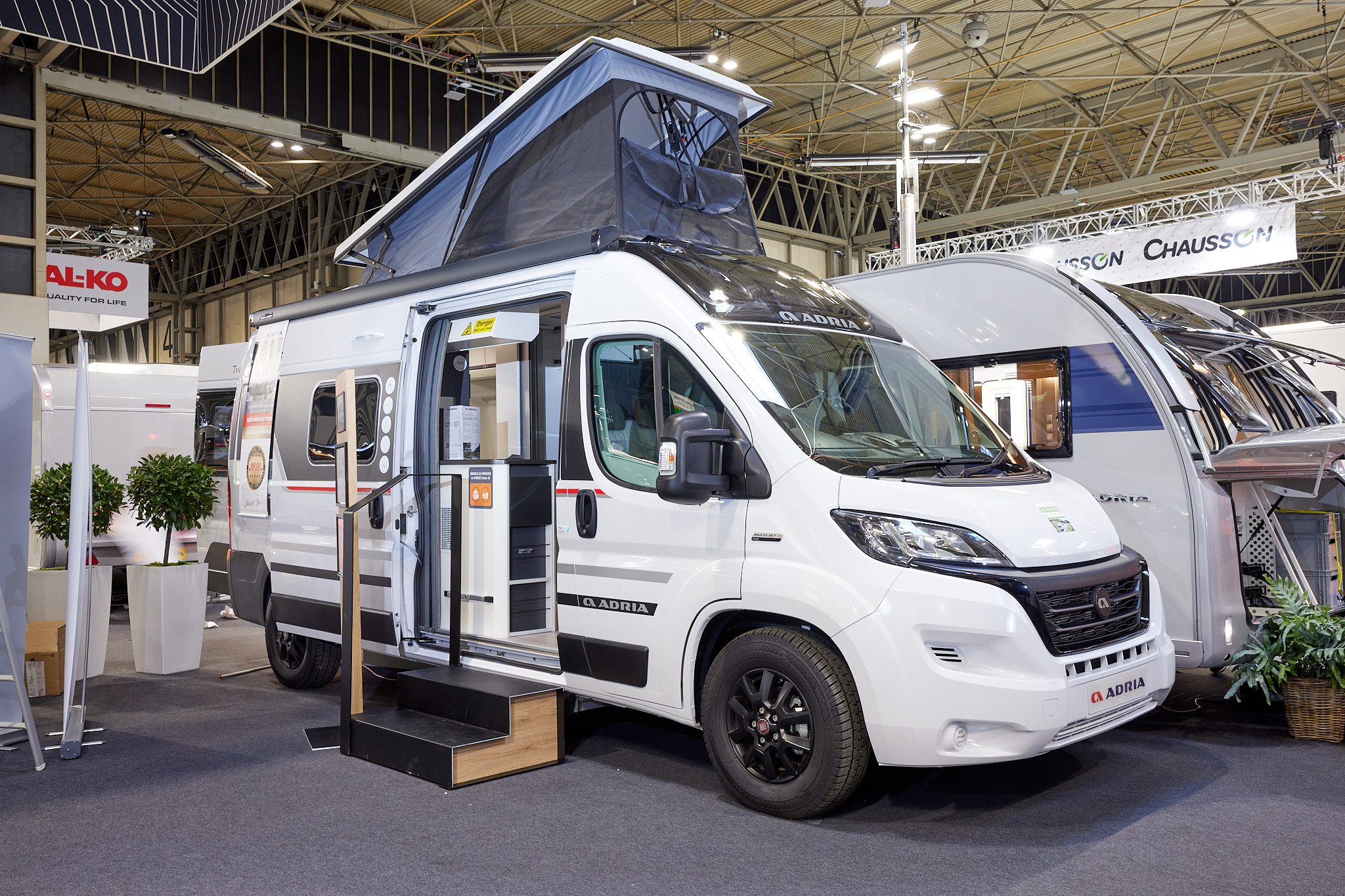 Adria Twin Sports 600 SPB exterior, van conversion is white, the sliding door is open showing into the interior, with a double step to gain easy access.  The rising roof is fully open with blue canvas.