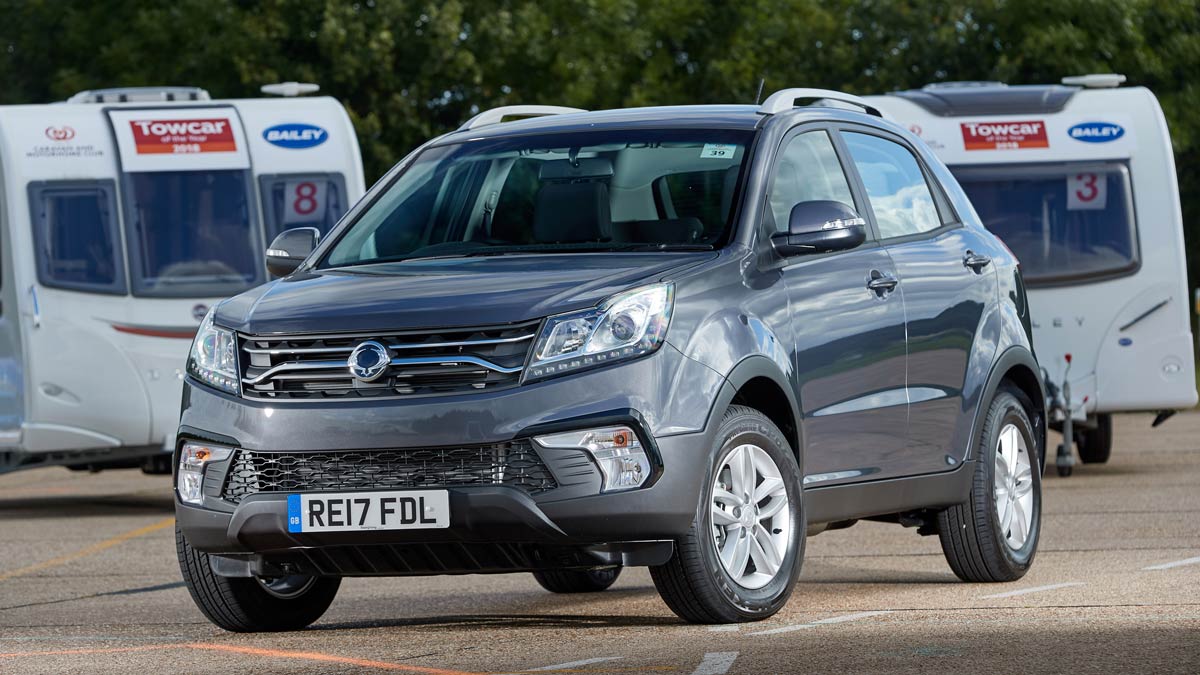 Dark grey Ssang Yong Korando car parked in front of two caravans