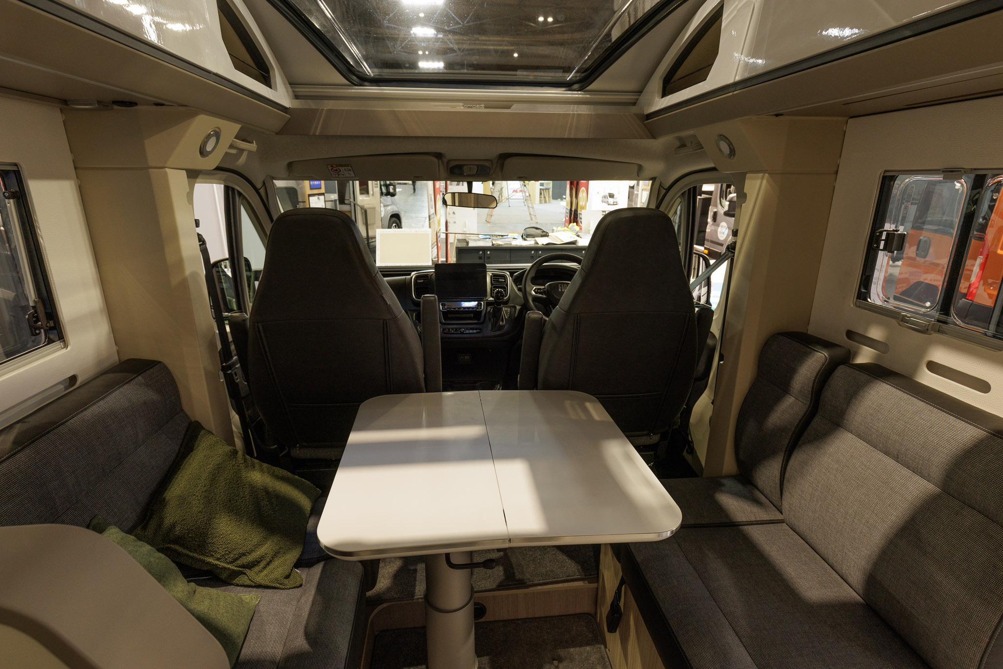 The Adria Compact Supreme DL has grey upholstery with leather trim.  It has a white extendable table.  There is a large sunroof.