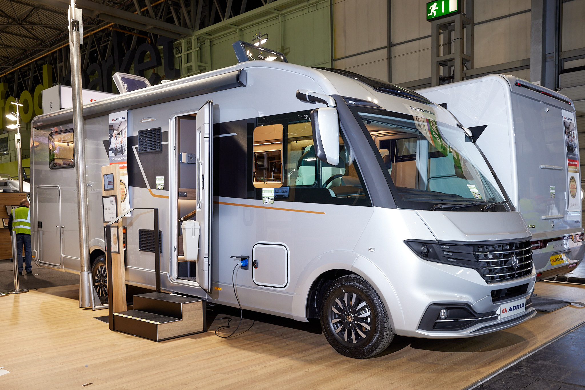 Adria Supersonic 780 SL exterior, the A class is silver, the habitation door is open showing into the interior, with a double step to gain easy access.  The two roof lights are fully open.