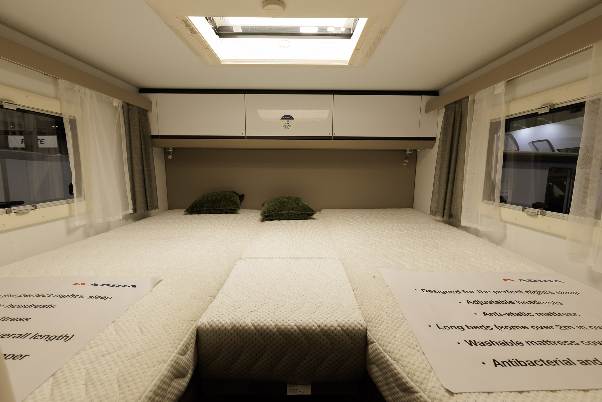 The Adria Compact Supreme DL has a rear fixed bed with white over head lockers and a window either side.  