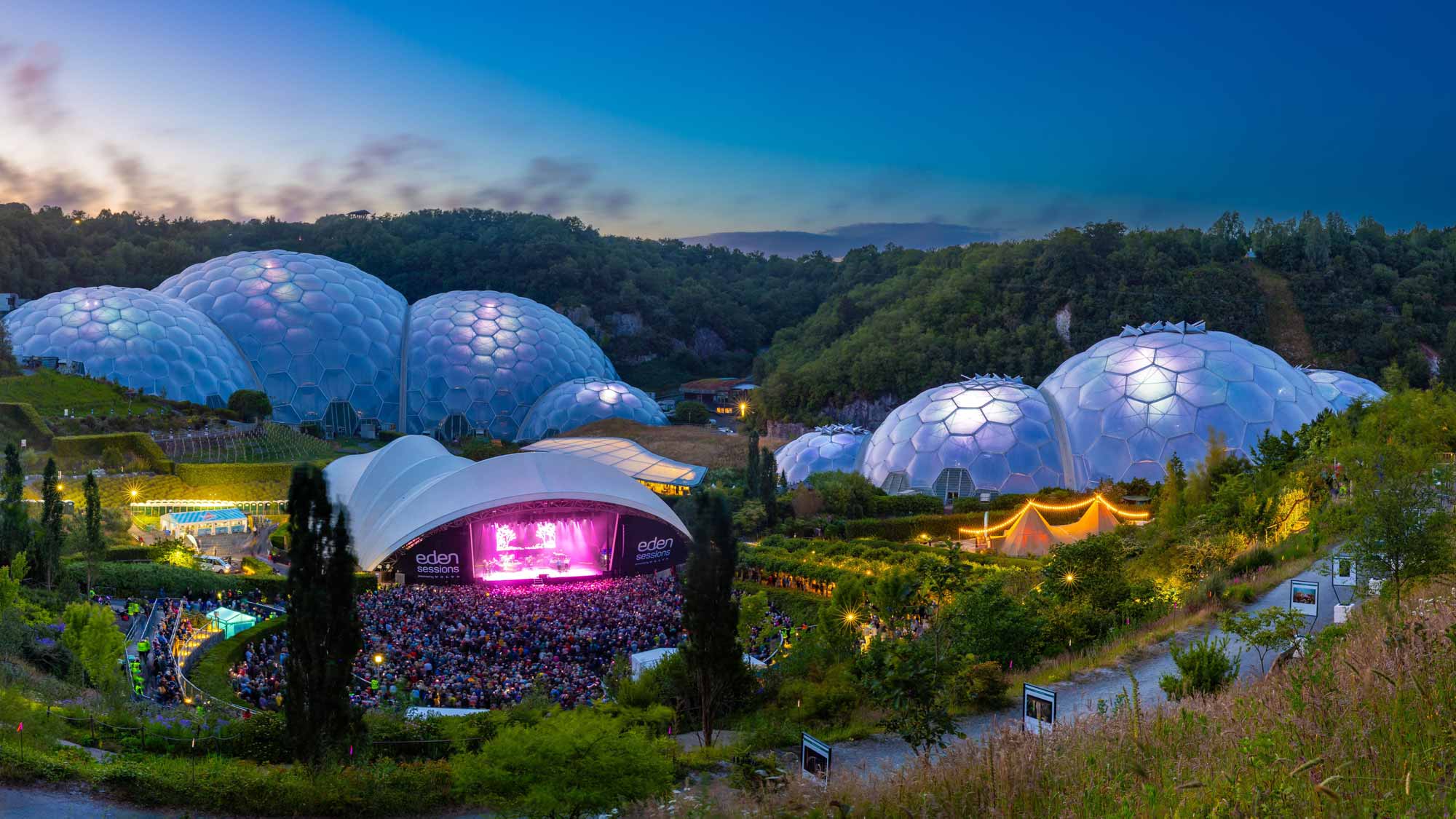 A brightly lit stage glows among the domes of the Eden Project