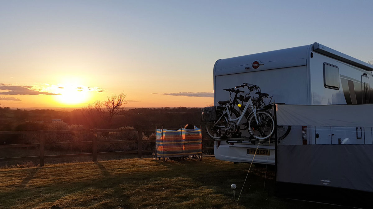 Caravan in a field at sunset