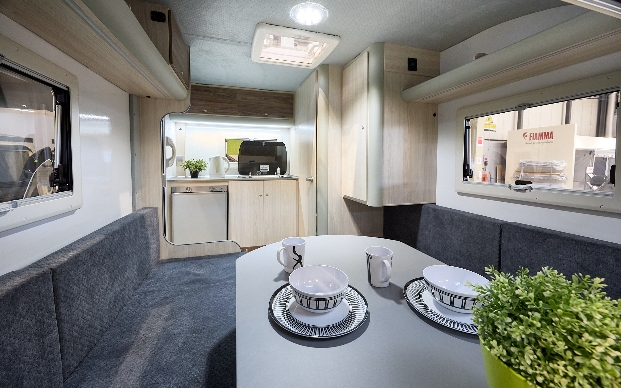 Campmaster King interior, blue upholstery, light wood furniture, rear kitchen, skylight