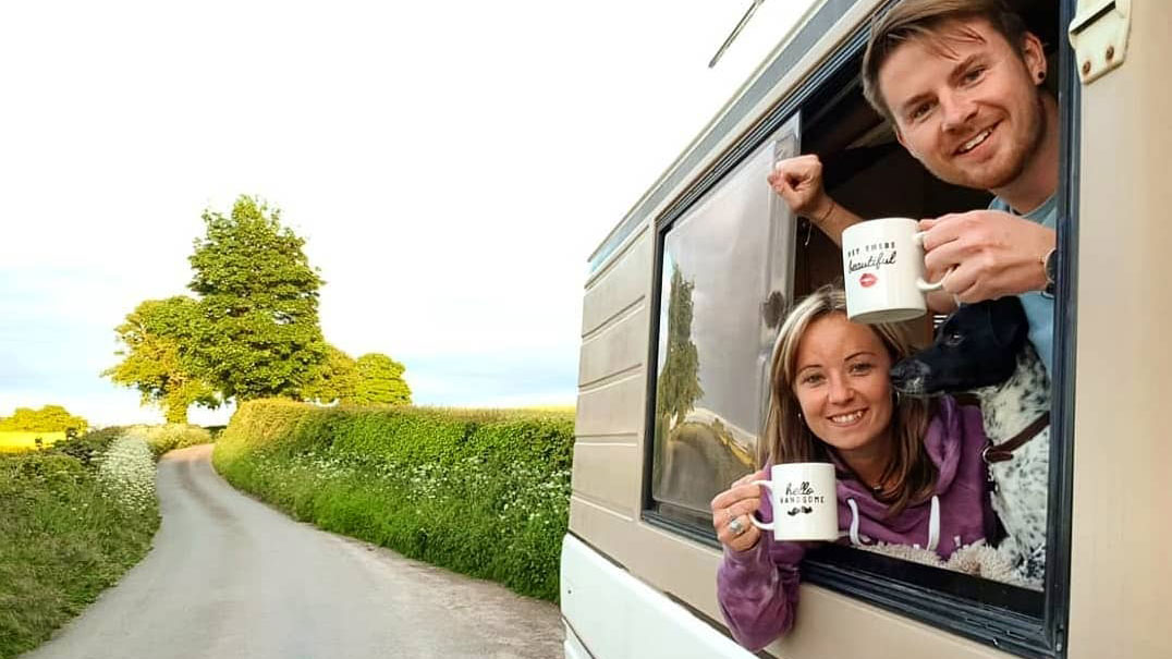 A couple relaxing in the window of a caravan, taking in the scenery