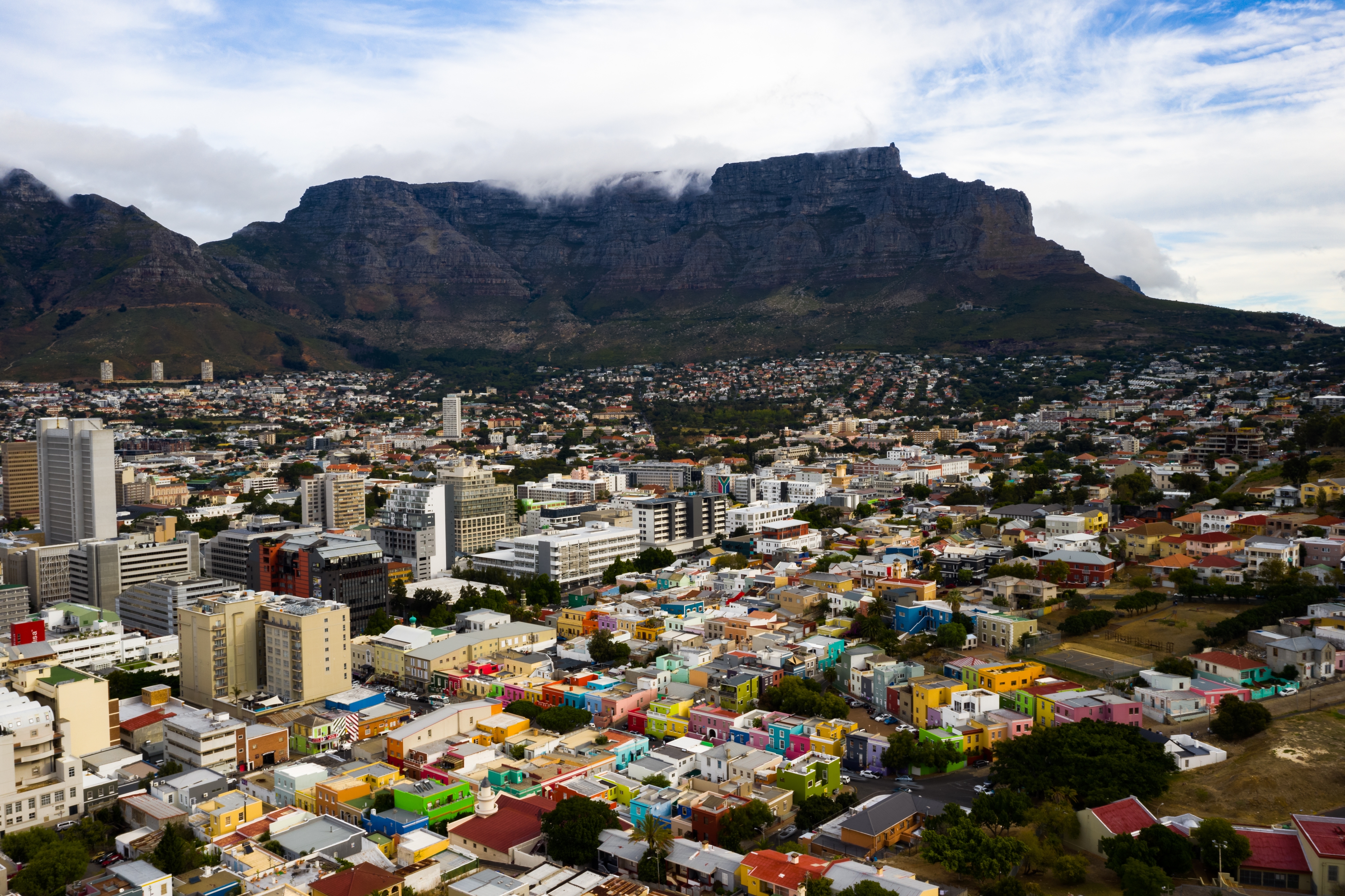 View from above of the brightly coloured buildings with the night mountains behind with the tops hidden in the clouds Cape Town, South Africa