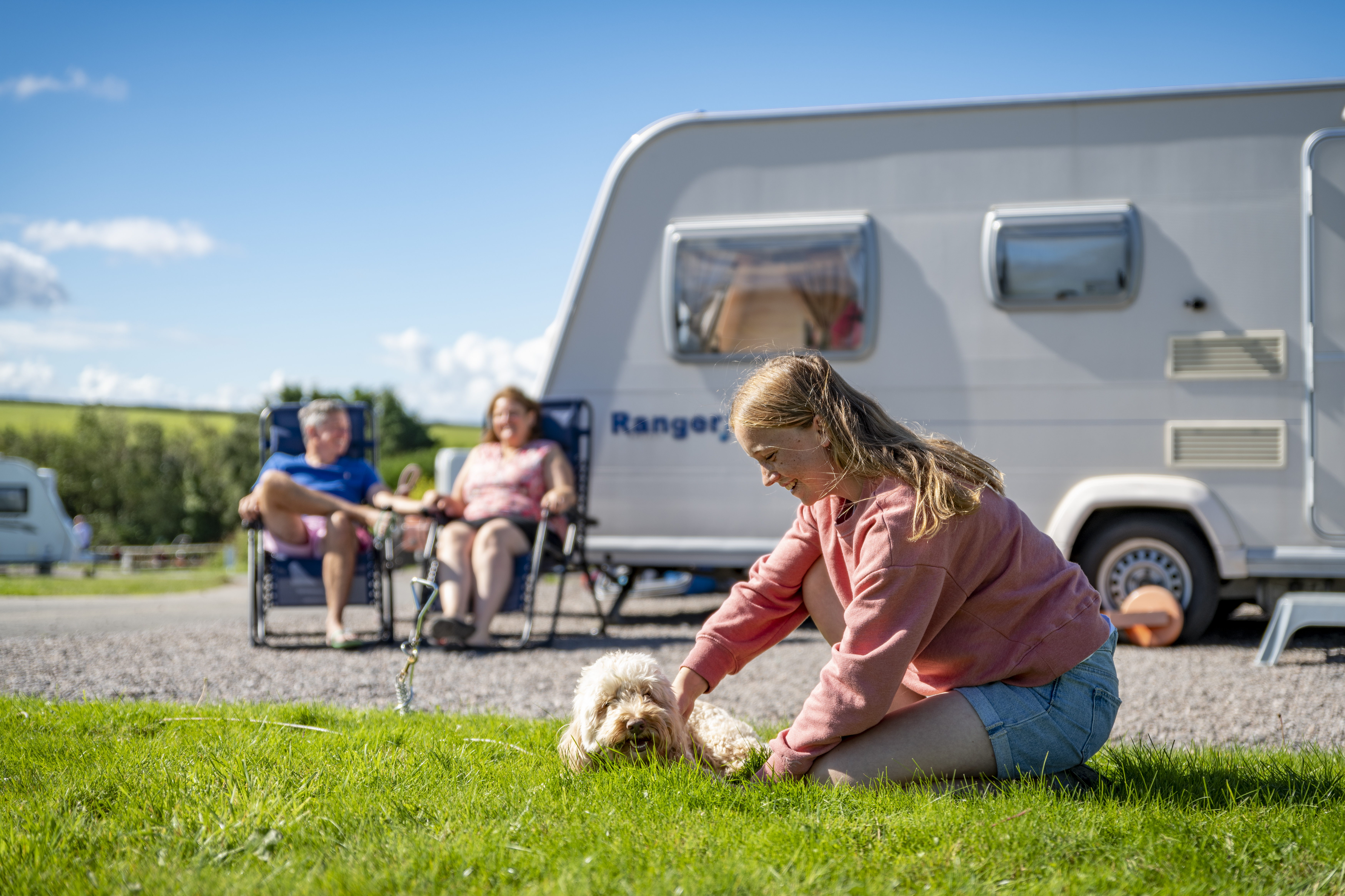 Girl playing with dog outside her caravan