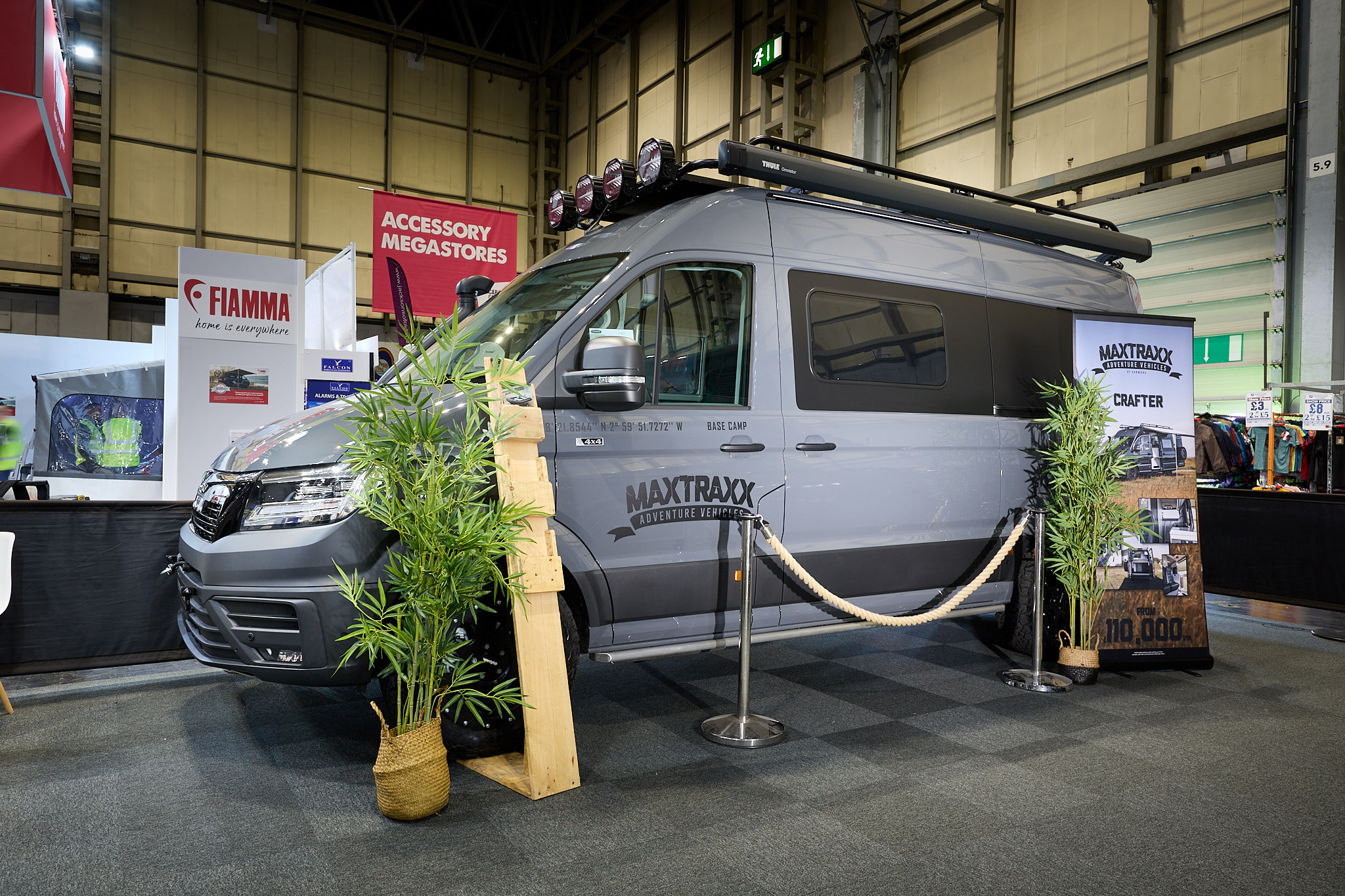 Vanworx MaxTraxx Crafter’s exterior is grey with black decals.  On the roof there is a folded awning and there are spot lights above the cab.  There are two palm trees either side of a roped off area.