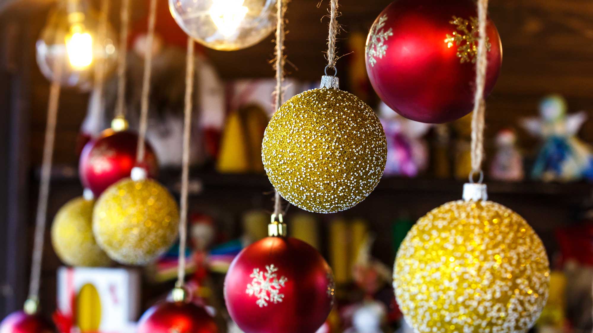 A selection of red and golden Christmas baubles hanging on the front of a market stall