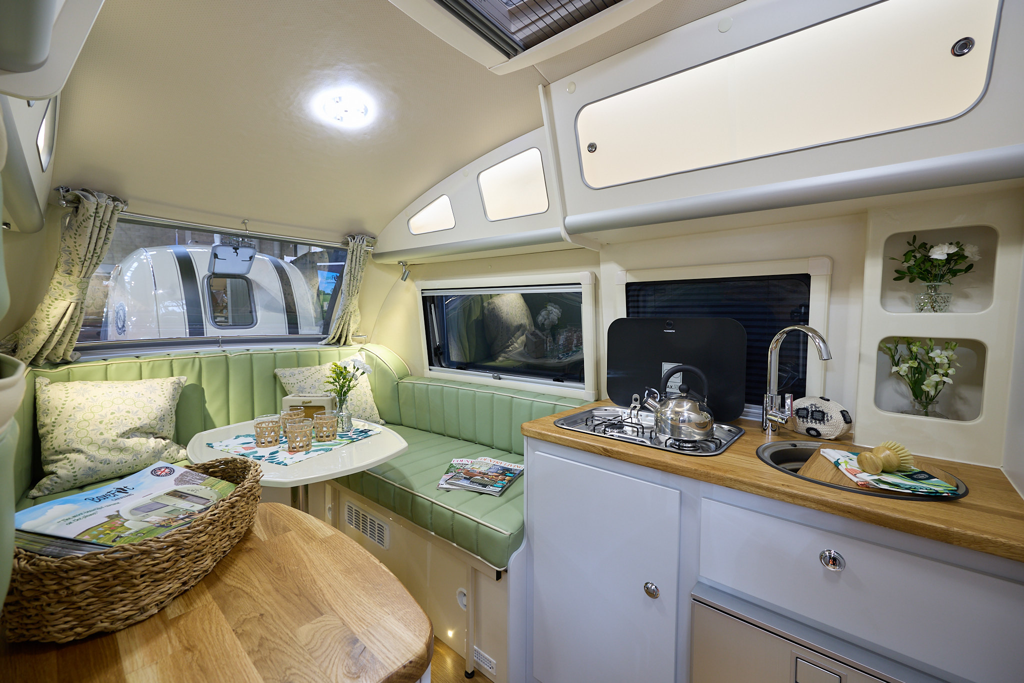 Barefoot Caravan Country Living x Barefoot’s interior is cream with pale green upholstery.  There are wooden work surfaces.