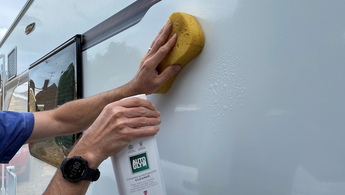 Cleaning the caravan's sidewall with sponge and Autoglym product