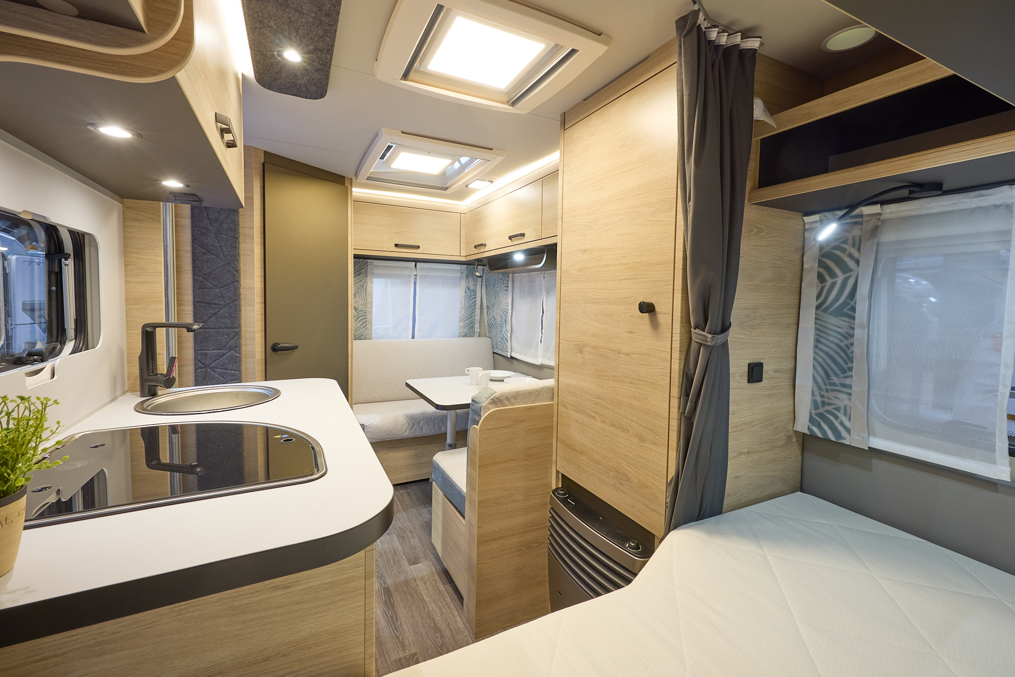 Interior of the Weinsberg CaraOne 390 QD with grey sofas, wood accents and a wooden floor.  The large roof light will let natural light flood in.  The French transverse fixed bed is at the front of the caravan.