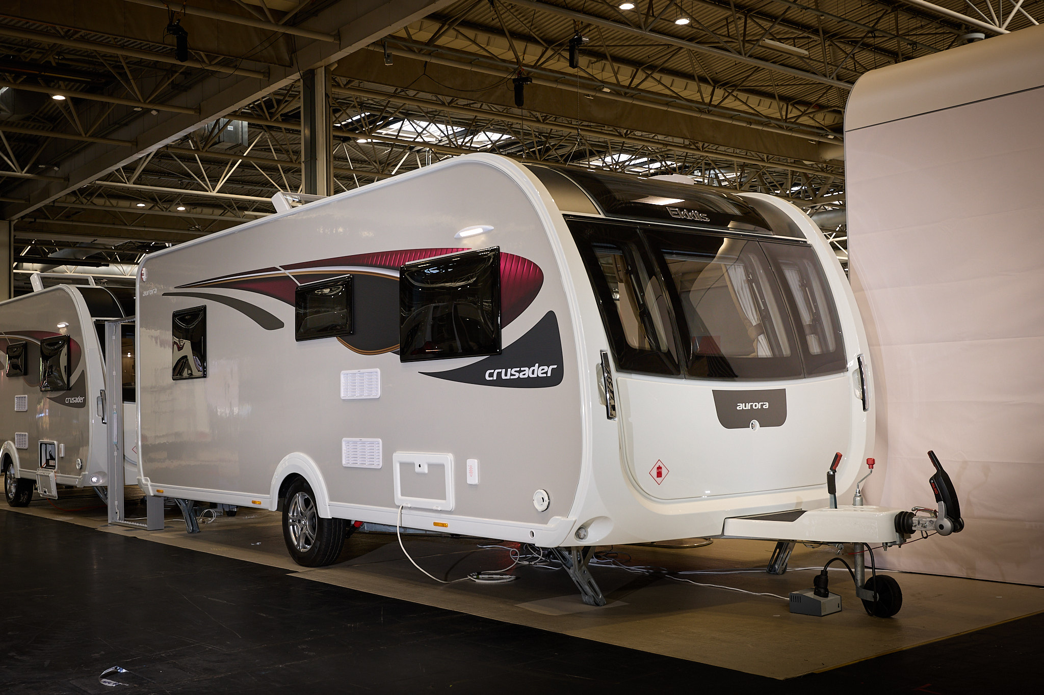 Elddis Crusader Aurora exterior is grey and white with black and red decals.  It has a large front window.