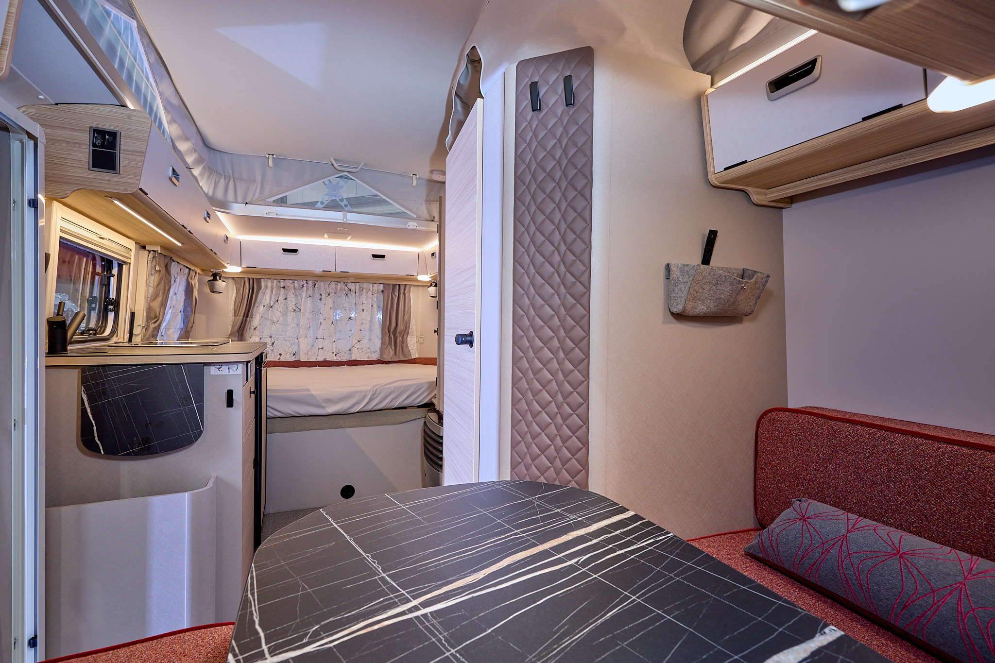 Eriba Touring 530 Urban Tango Red interior, it is white and cream with red upholstery.  There is a dinette at the front.  The fixed bed is beyond the kitchen.  