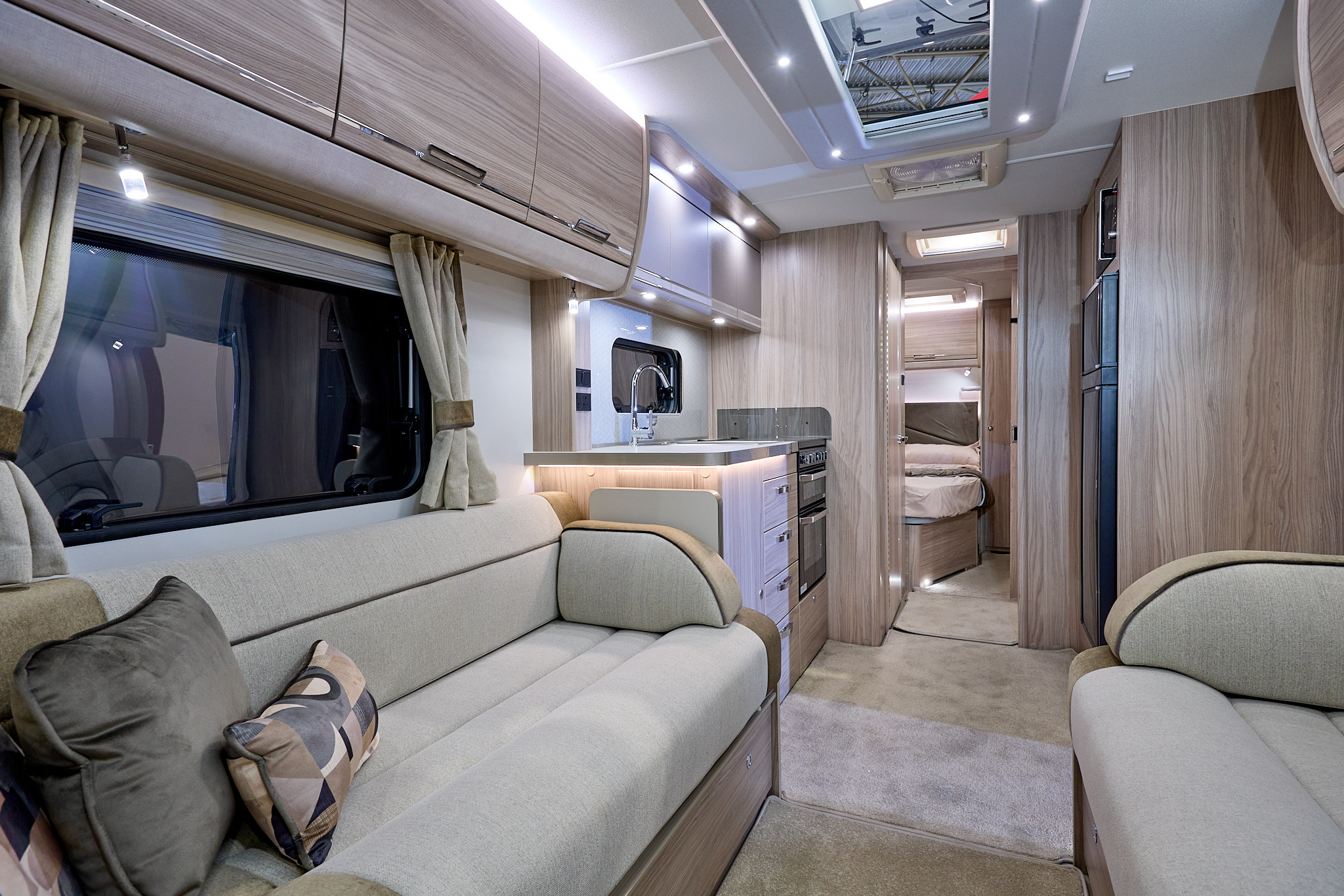 Elddis Crusader Tempest's interior has pale wood furniture and its upholstery is gold and cream with black piping.  The bedroom is to the rear and it has a large skylight.