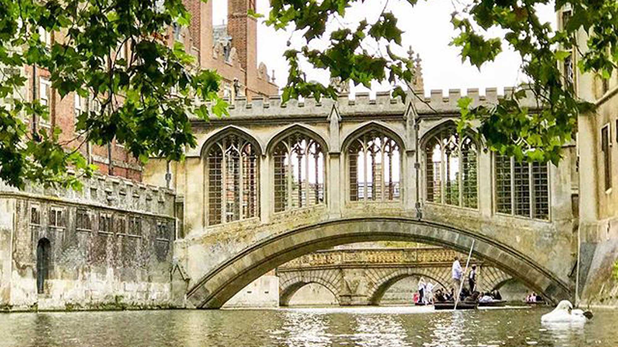 Punt on the River Cam passing under an ornate covered bridge
