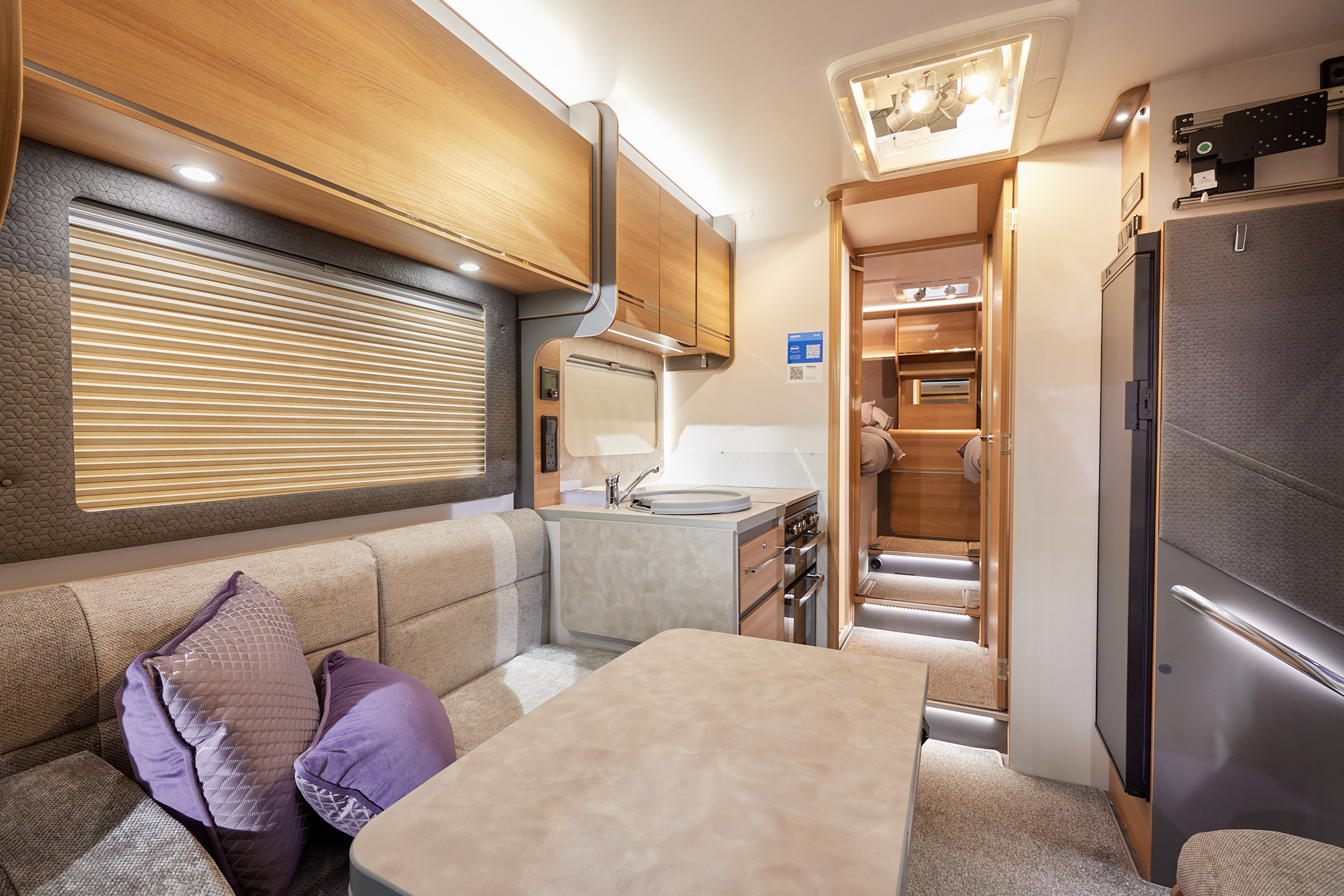 Bailey Adamo 75-4T has beige upholstery, with wooden overhead lockers.   The kitchen has a round sink and a flap to extend kitchen work surface.  The vehicle has a rear bedroom with two fixed single beds.