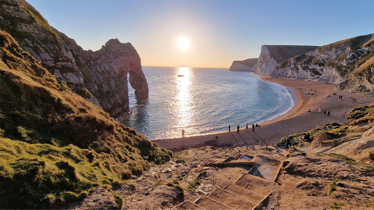 A beautiful sunset over a bay with vibrant orange and pink colours reflecting on the water