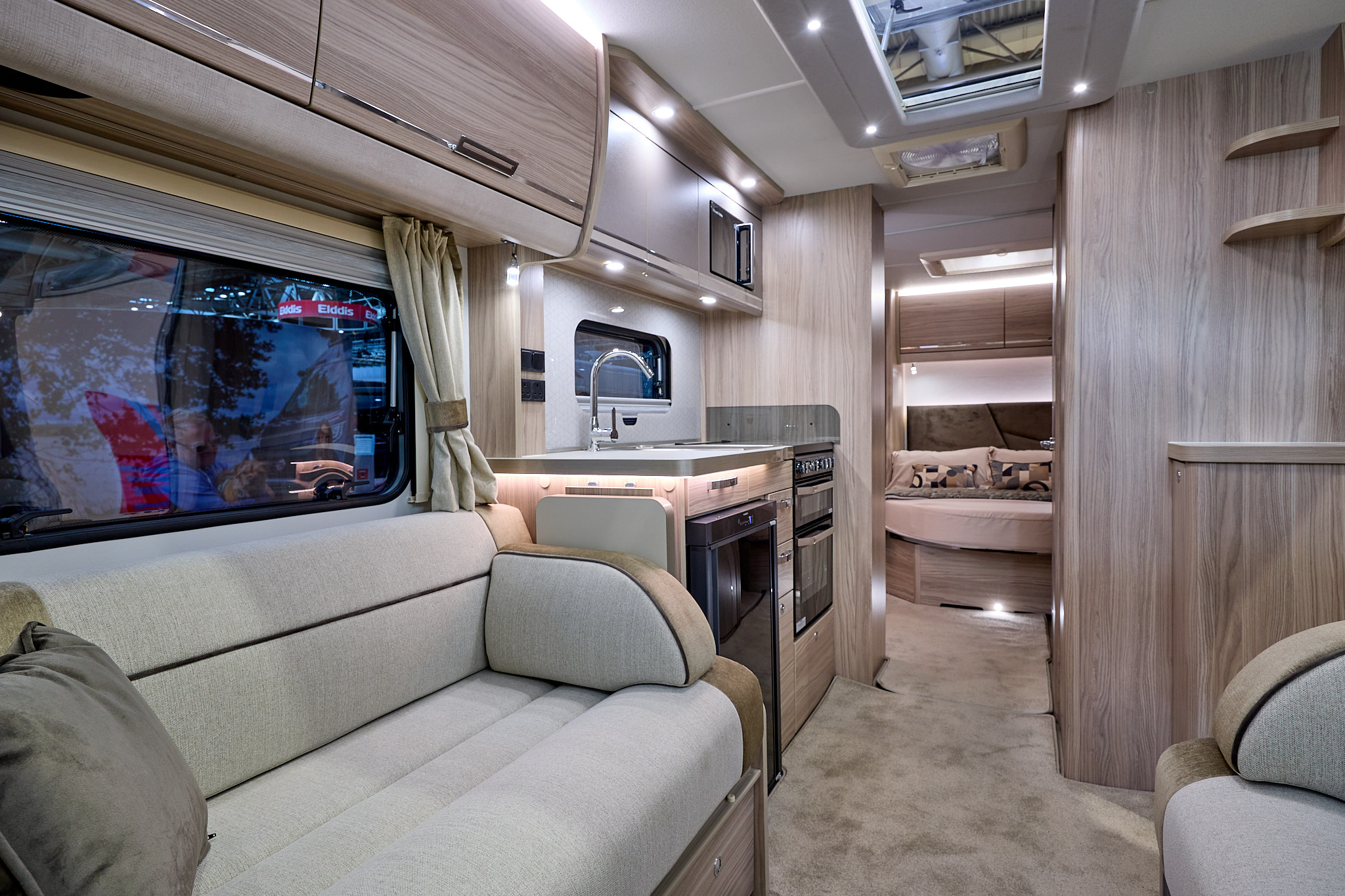 Elddis Crusader Aurora's interior has pale wood furniture and its upholstery is gold and cream with black piping.  The bedroom is to the rear and it has a large skylight.