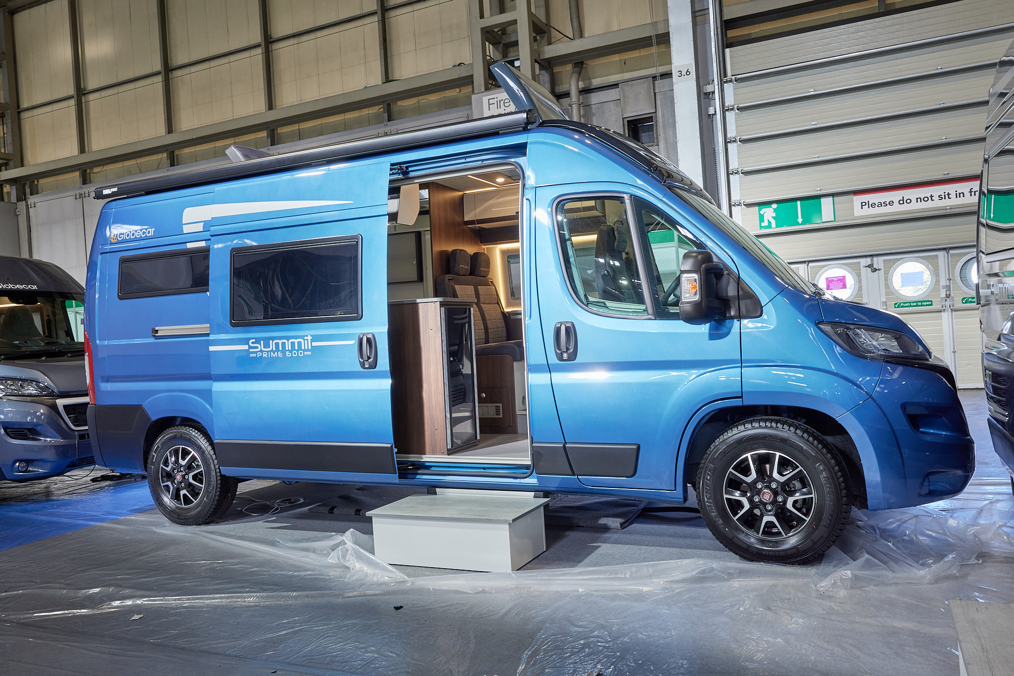 Globecar Summit Prime 600, the vehicle has a blue exterior and its sliding door is open showing into the interior, with a step to gain easy access.  