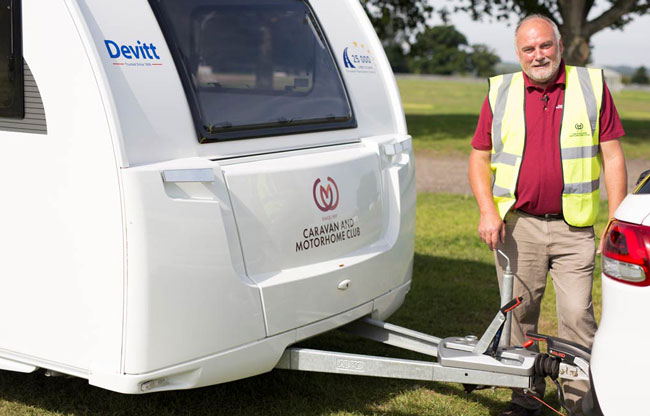 Man in high vis stood next to caravan a frame
