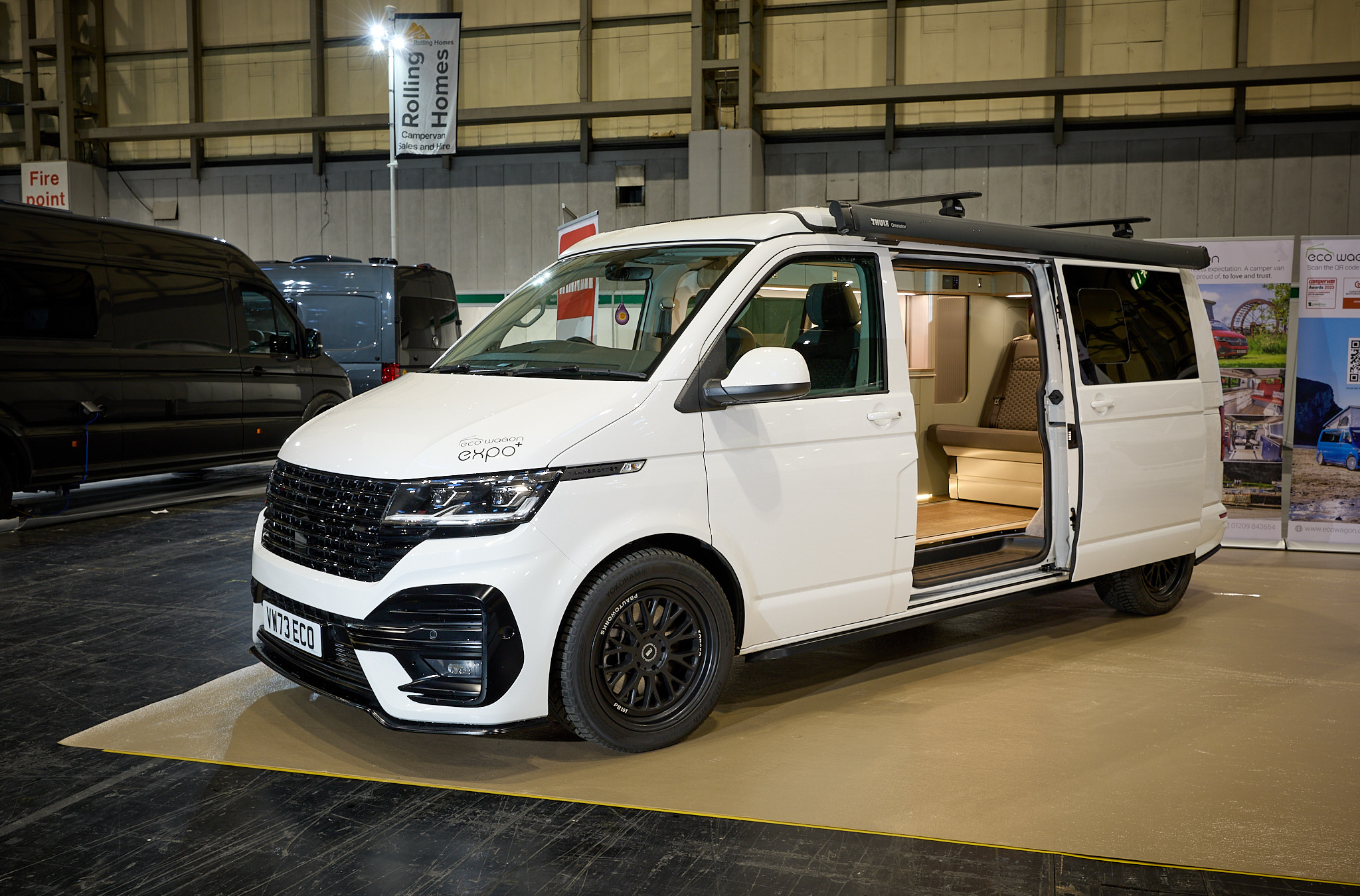 Ecowagon Expo+’s exterior is white with black decals.  The entrance door is open revealing the lounge and there is a built in step to gain easy access.