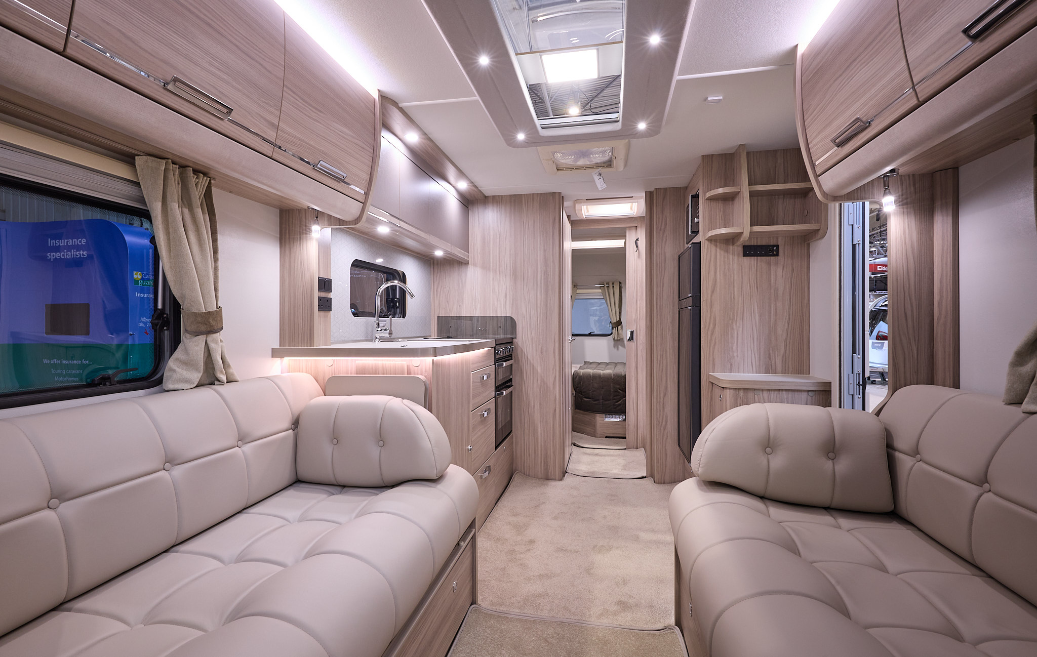 Elddis Crusader Zephyr's interior has pale wood furniture with beige leather upholstery.  The bedroom is at the rear and there is a large skylight.