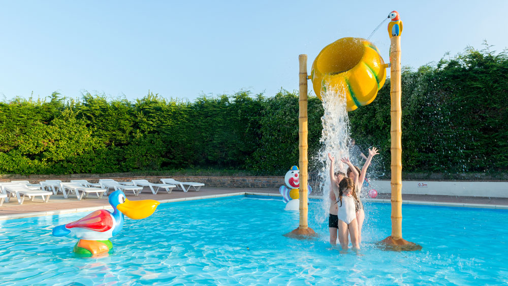 Children playing under water feature in swimming pool at Hillhead Caravan Club site in the summer