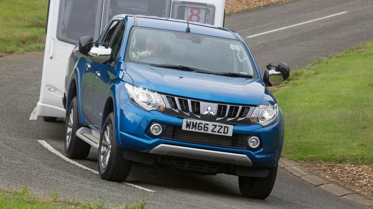 Blue Mitsubishi car towing a caravan along a road close up