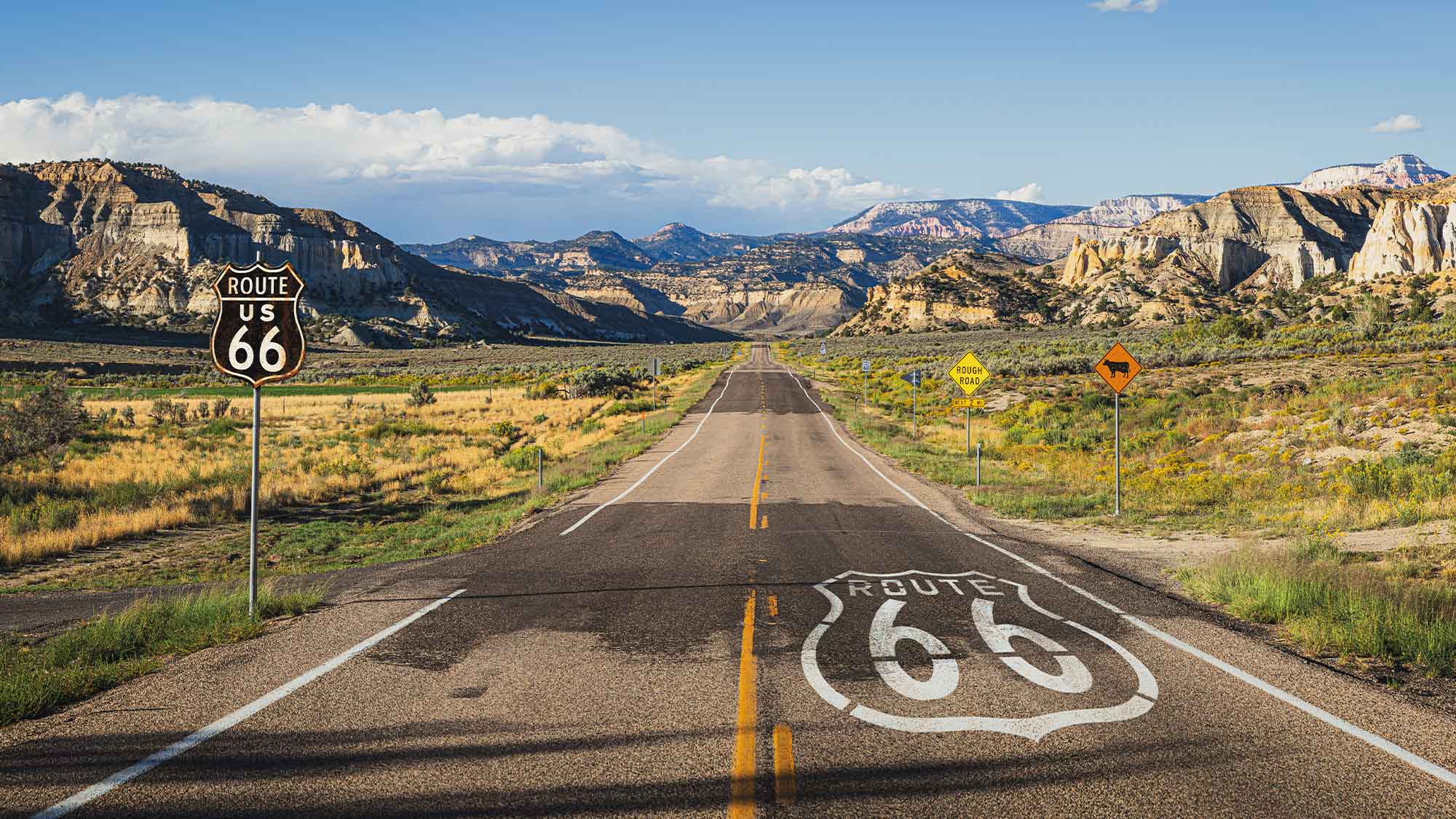 Scenic road with route 66 sign on the tarmac on the road heading towards the mountains in the distance