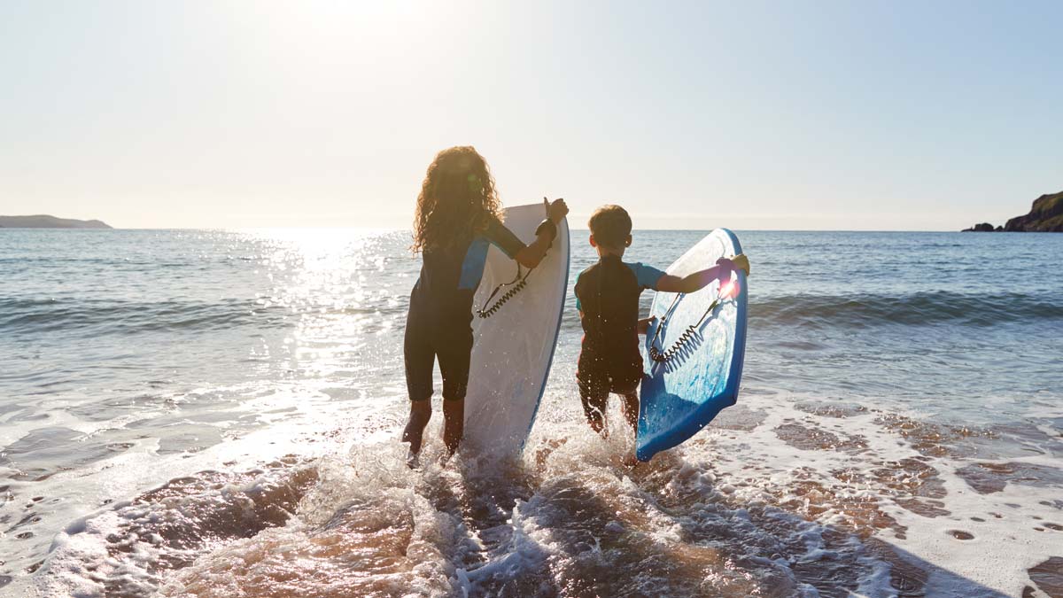 children bodyboarding on a UK beach