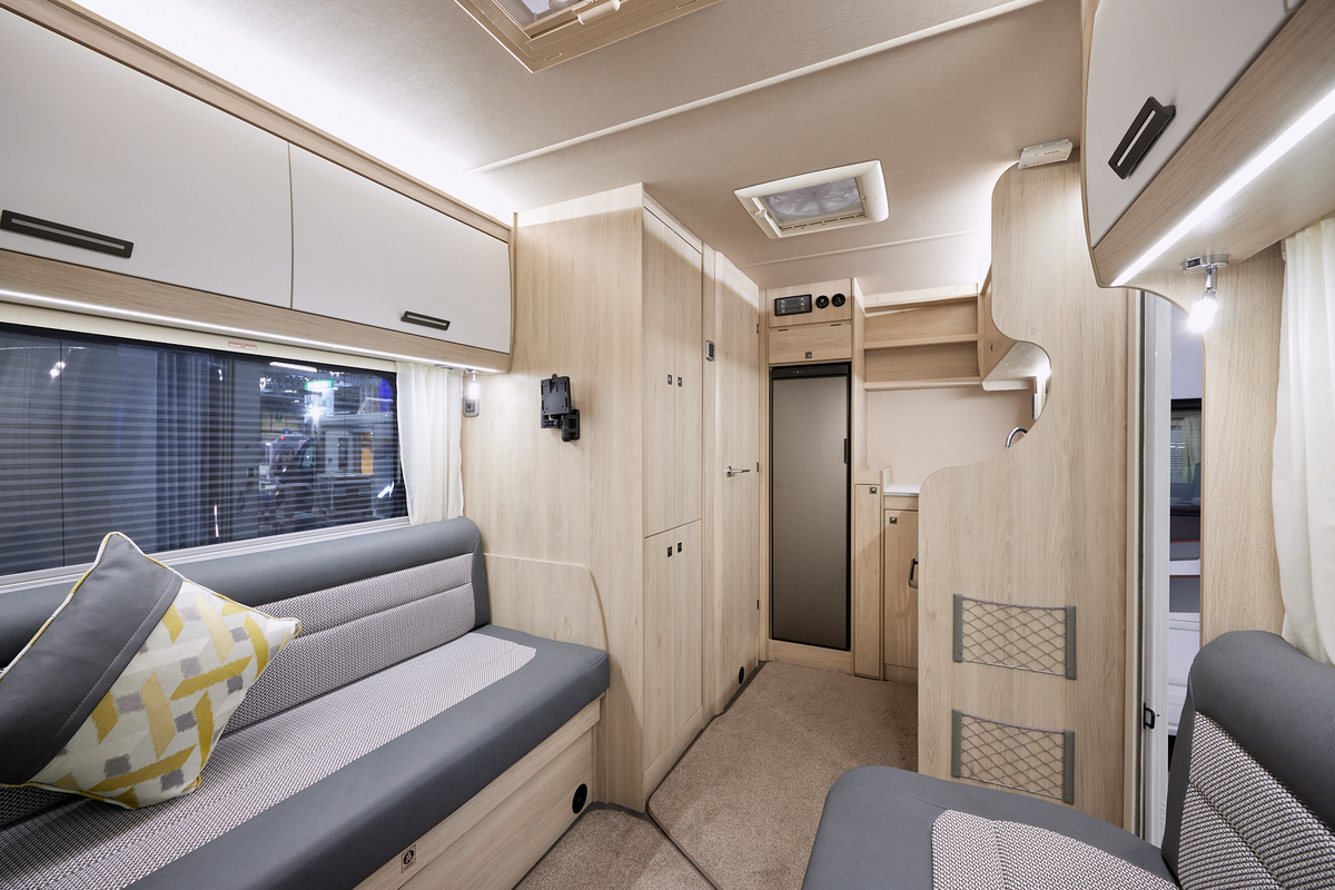 Auto-Trail F-Line F62 has two tone upholstery, with pale wooden furniture.  There is an extractor fan in the kitchen ceiling.  The floor has removable beige carpet. 