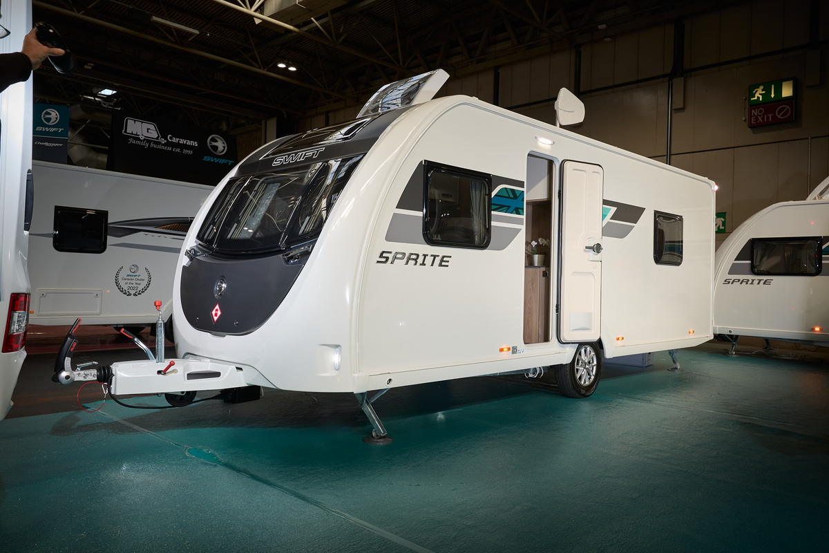 Swift Sprite Grande Quattro FB has a white exterior with grey and turquoise graphics, it has a black panel under the front window and its skylight is open.  It has a single axle.
