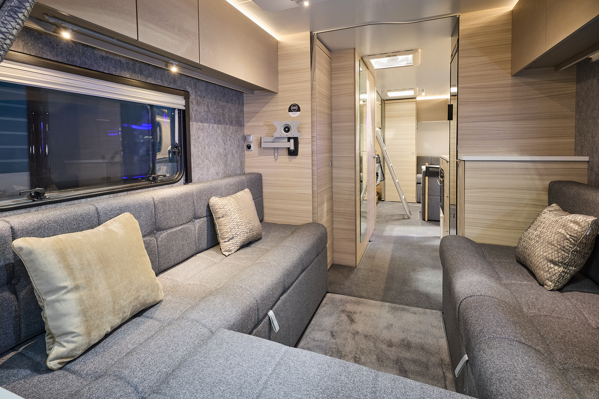 The Adria Altea 622 DK Avon has a front u shaped grey sofa with beige cushions.  The furniture is pale wood.  Towards the rear there is a ladder to gain easy access to the rear fixed bunks.