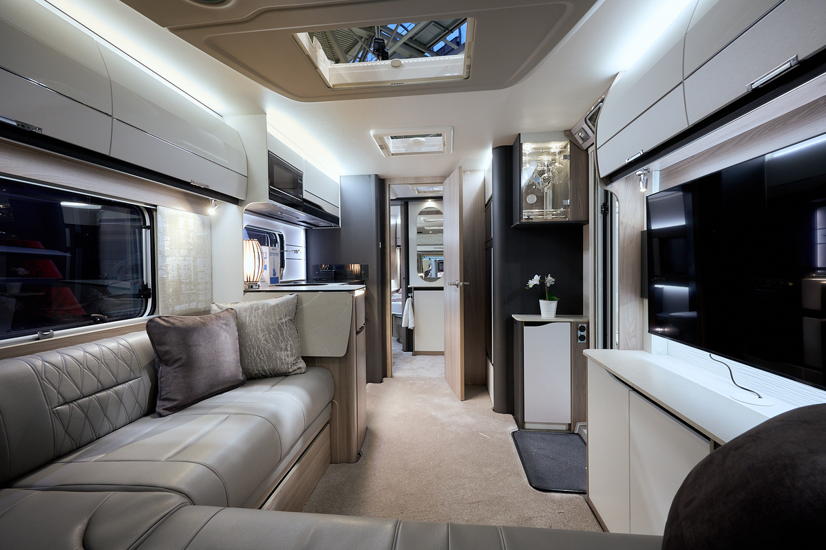 Swift Elegance Grande 850 interior, L shaped lounge, beige leather upholstery, white overhead lockers, large TV, lounge, kitchen, washroom, bedroom, three skylights