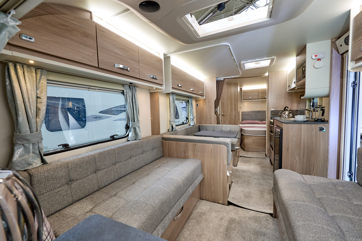 Swift Sprite Grande Quattro FB's interior has wooden furniture with beige upholstery and carpet.  The bedroom is to the rear.  The skylight is open.
