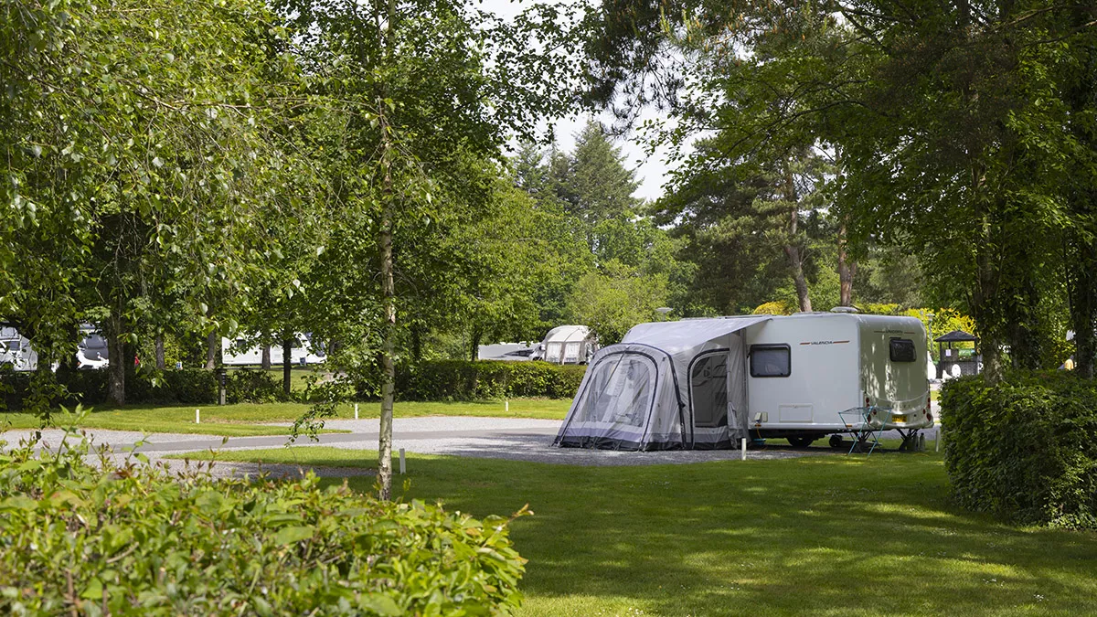 Caravan with awning pitched in the shade at Stover Club Campsite.