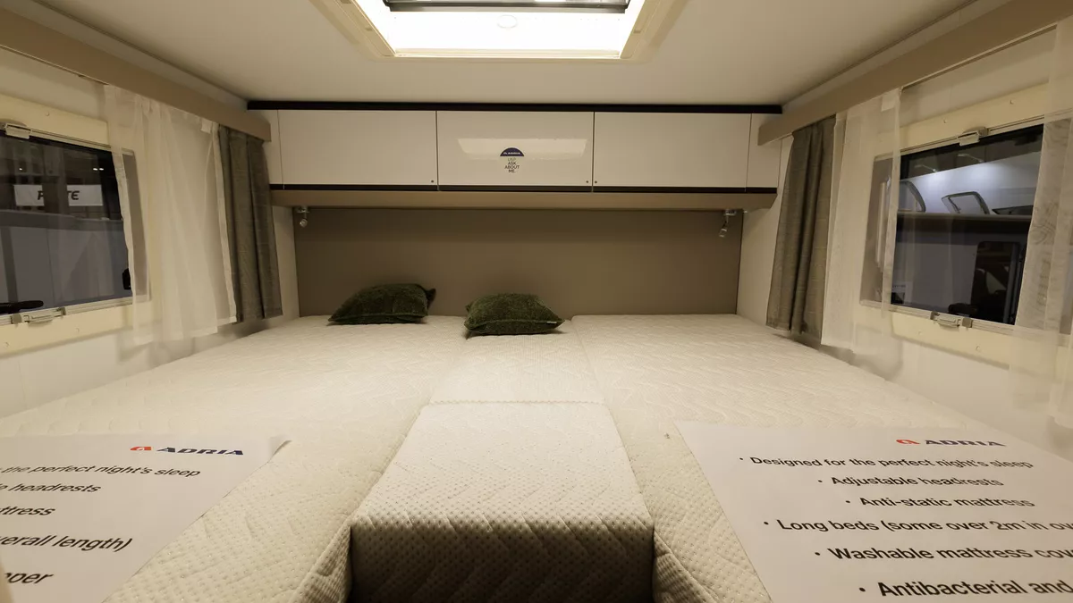 The Adria Compact Supreme DL has a rear fixed bed with white over head lockers and a window either side.  