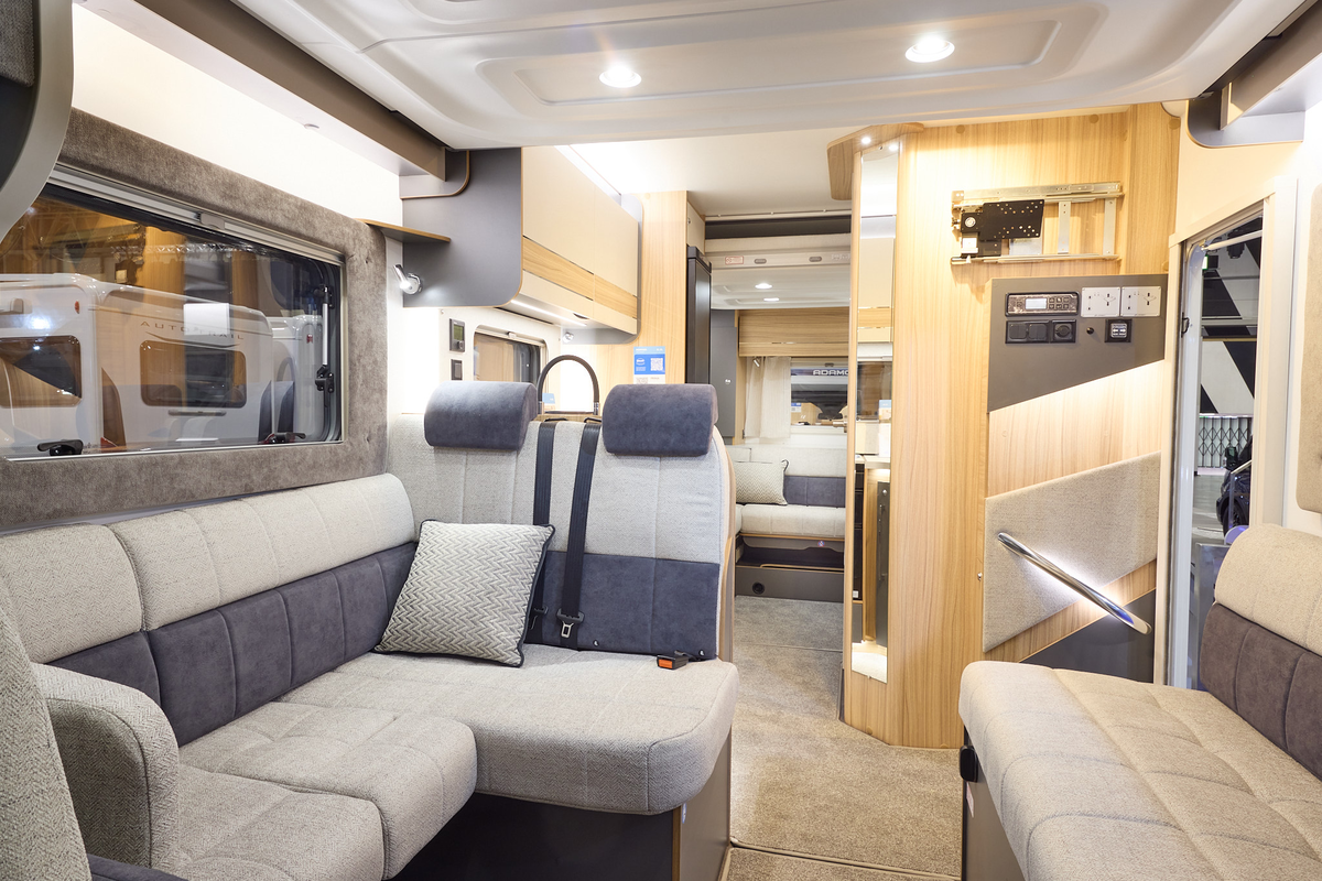 The Bailey Adamo XL DL has beige carpets, with cream and pale wood cabinets.  The upholstery is cream and dark brown.  There is another lounge to the rear.  