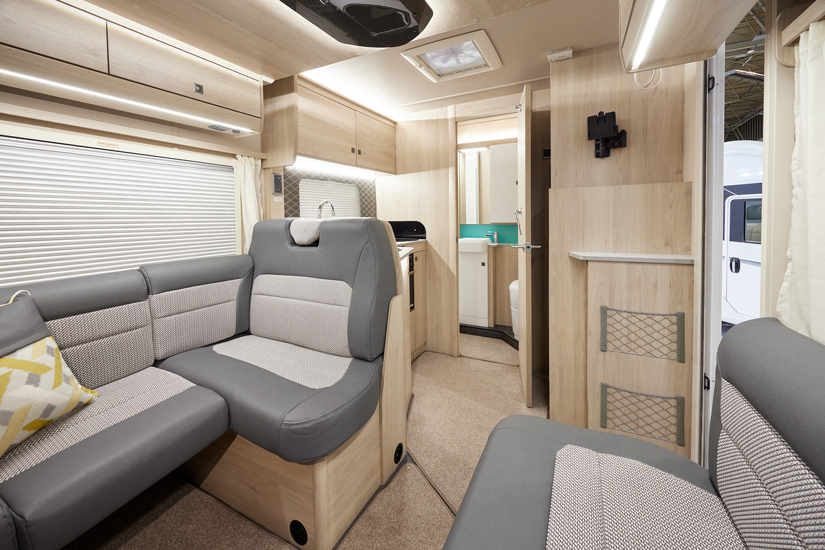 Auto-Trail F-Line F60 has two tone upholstery, with pale wooden furniture.  There is an extractor fan in the kitchen ceiling.  The floor has removable beige carpet. 