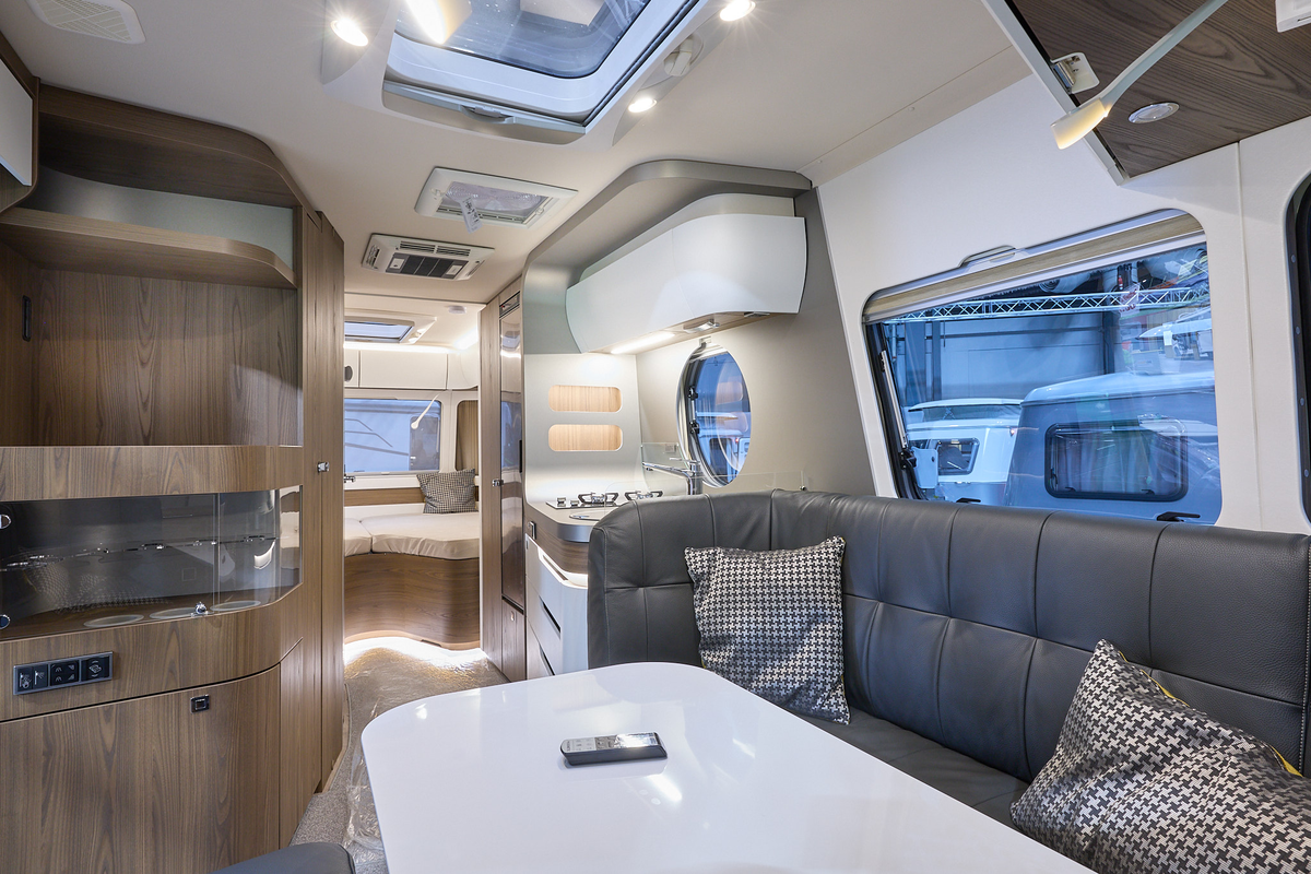 Eriba Touring 820 interior, black upholstery, white table, wooden units, fixed bed, three skylights