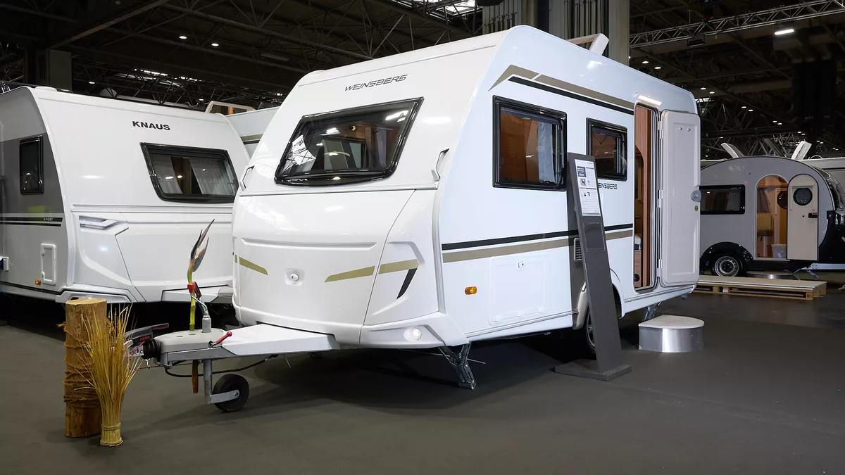Weinsberg CaraOne 400 LK Dinette's exterior is white with brown and gold graphics.  The door is open and there is a step to enable easy access to the interior.