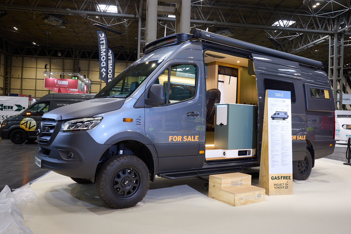 Project Yonder Freedom 4X Utility has a metallic blue exterior with black trim.  There are two steps leading to the open habitation door which reveals the interior.