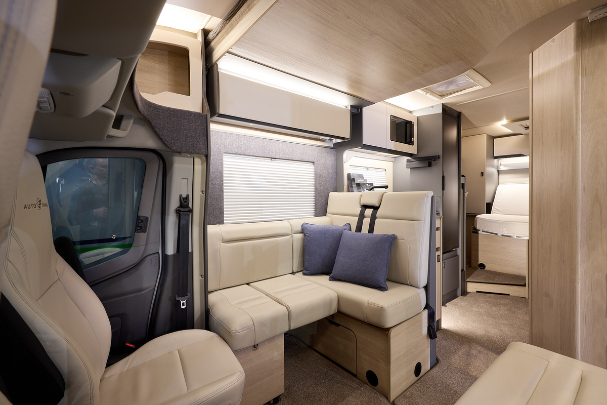 The Auto-Trail F-Line F74 has beige carpets, with pale wood cabinets with cream overhead lockers.  The upholstery is cream leather.  There is a step leading to the rear fixed bed.