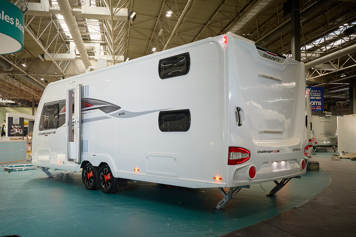 Swift Challenger Grande SE 670's exterior is white with grey and red graphics.  The caravan is a twin axle and has its corner steadies down.