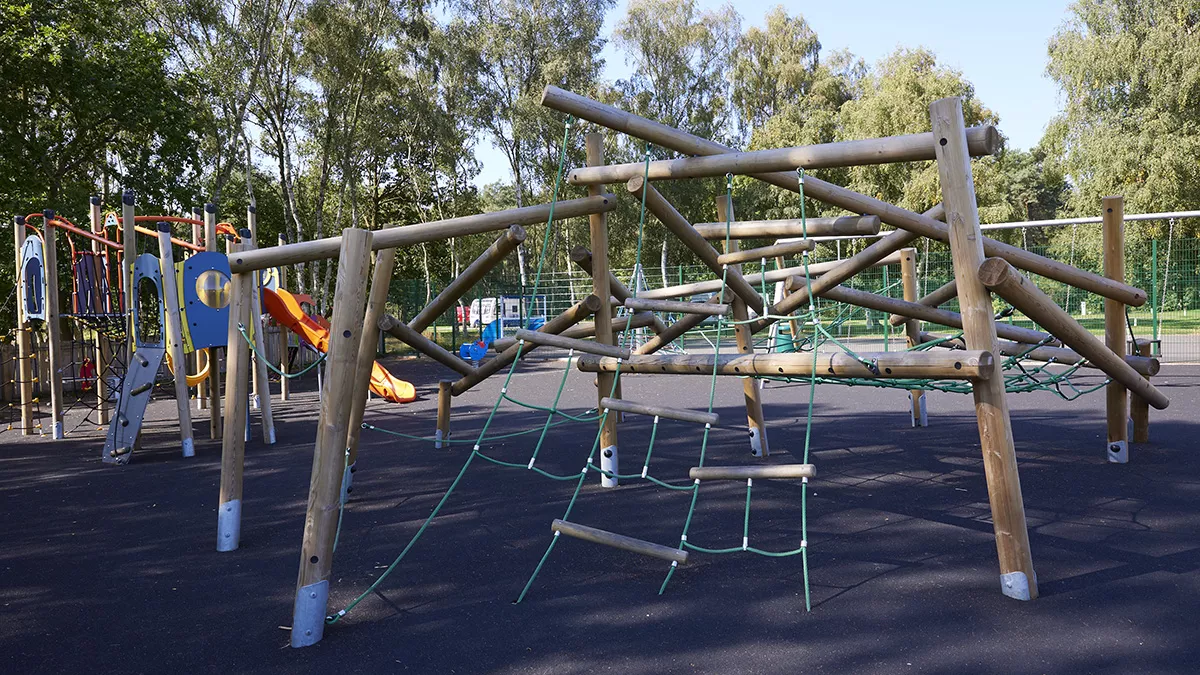  A wooden playground structure featuring a climbing area for children to explore and play.