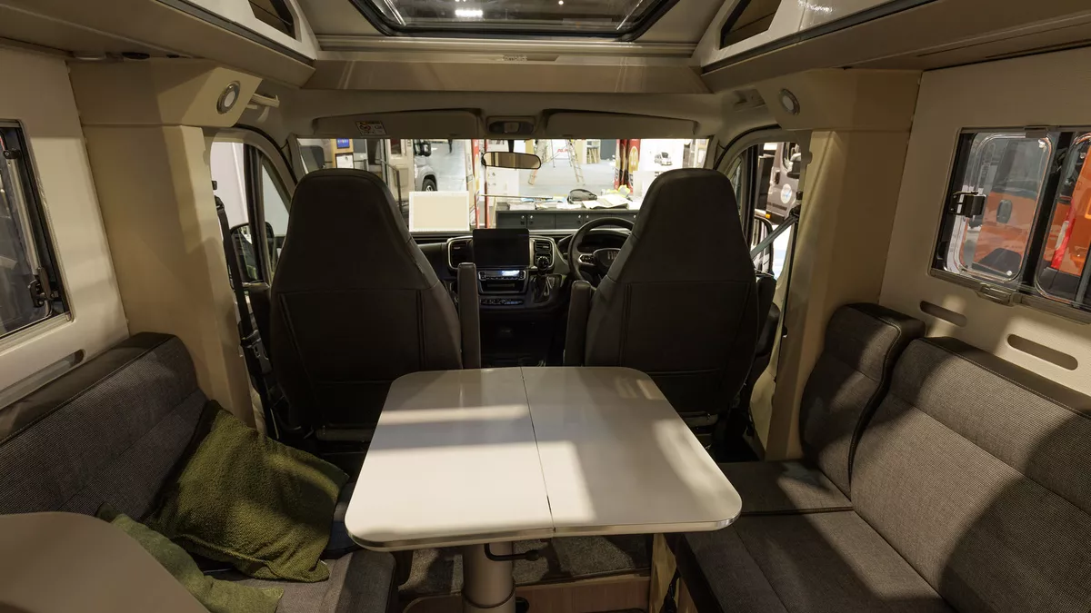The Adria Compact Supreme DL has grey upholstery with leather trim.  It has a white extendable table.  There is a large sunroof.