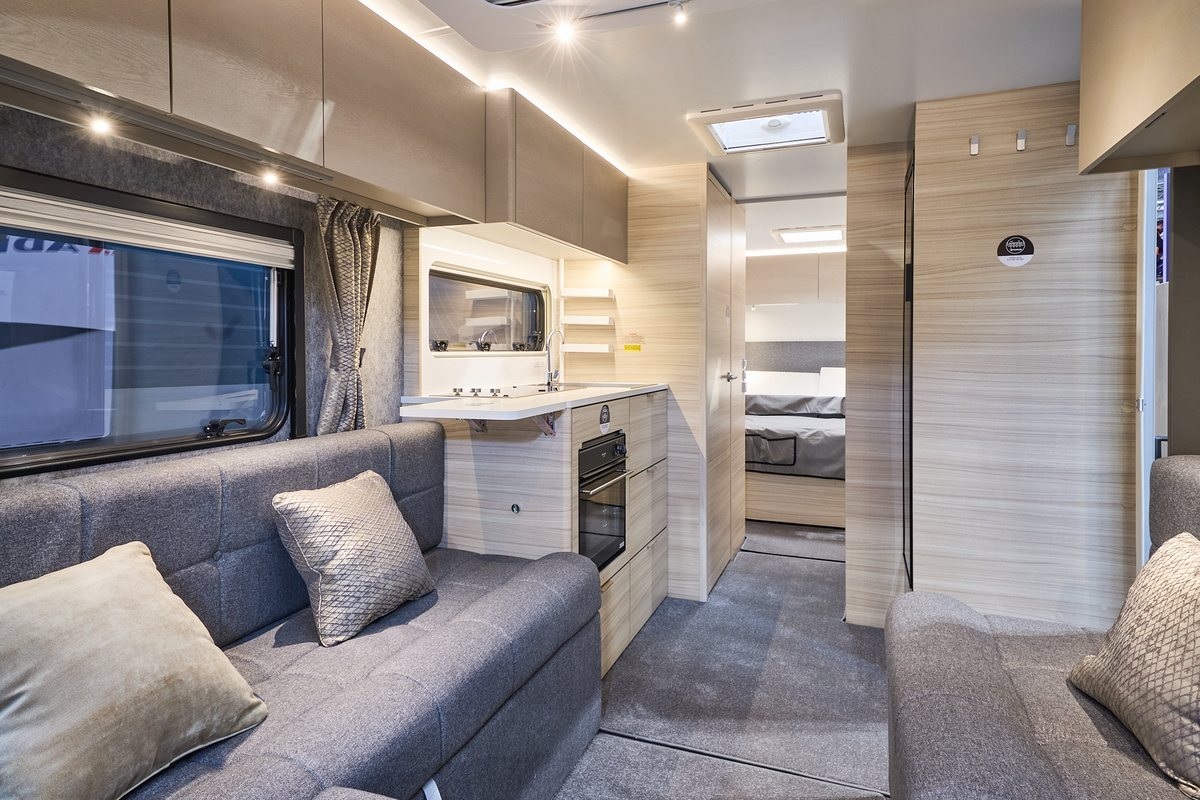 The Adria Altea 622 DP Dart has a front u shaped grey sofa with beige cushions.  The furniture is pale wood.  Towards the rear there is a fixed island bed.