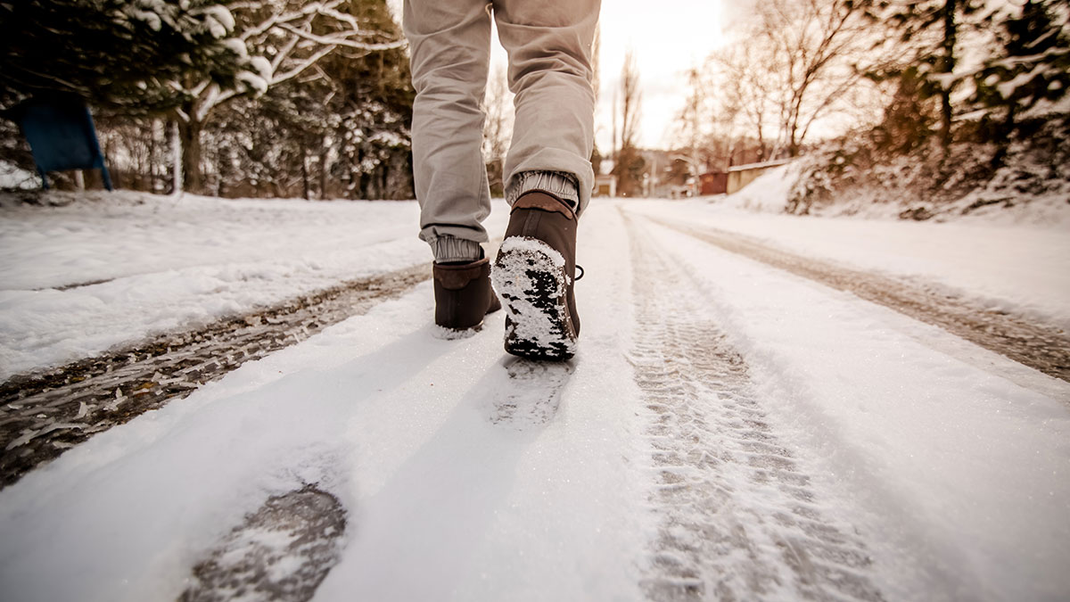 Photo of a man in walking boots, walking across a snow covered forest